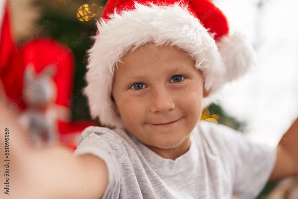 Adorable toddler make selfie by camera standing by christmas tree at home Adorable toddler make selfie by camera standing by christmas tree at home