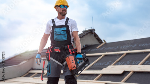 Canvastavla A carpenter with tool belt is holding a electric nailer  in his hand on-the-job on the roof