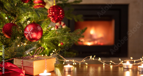 Christmas tree decoration and Xmas presents on table  burning fireplace background