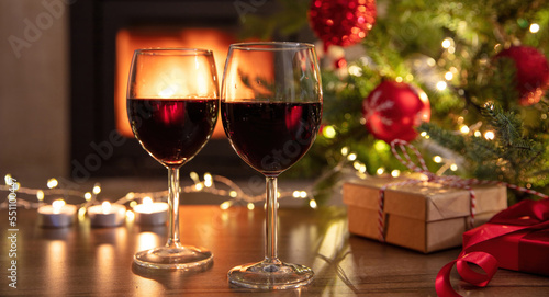 Red wine and Christmas decoration on table  fireplace background. Xmas celebration