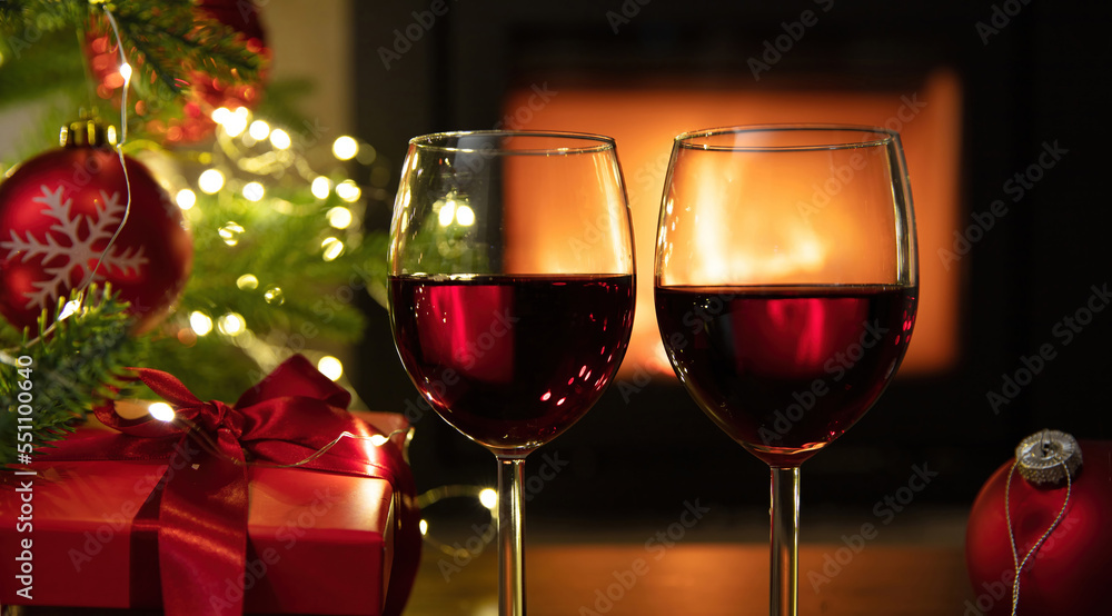 Christmas celebration. Red wine glasses, Xmas presents and decoration on table, fireplace background. Xmas celebration Christmas celebration. Red wine glasses, Xmas presents and decoration on table, fireplace background. Xmas celebration