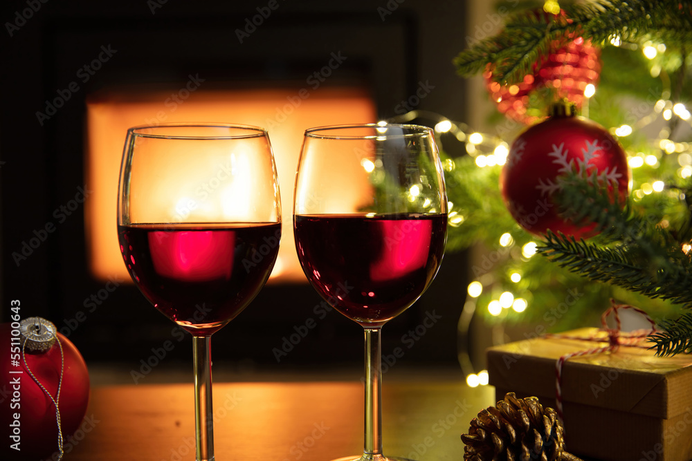 Christmas celebration. Red wine glasses, Xmas presents and decoration on table, fireplace background. Xmas celebration Christmas celebration. Red wine glasses, Xmas presents and decoration on table, fireplace background. Xmas celebration