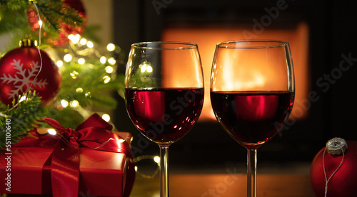Christmas celebration. Red wine glasses  Xmas presents and decoration on table  fireplace background. Xmas celebration