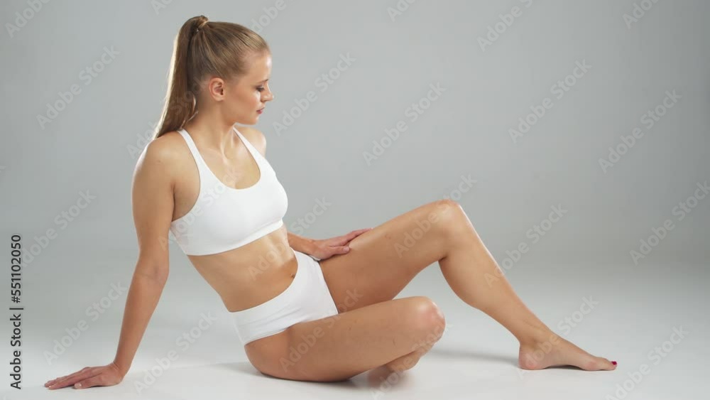 Young, fit and beautiful blond woman in white swimsuit posing over grey background. Healthcare, diet, sport and fitness concept. Young, fit and beautiful blond woman in white swimsuit posing over grey background. Healthcare, diet, sport and fitness concept.