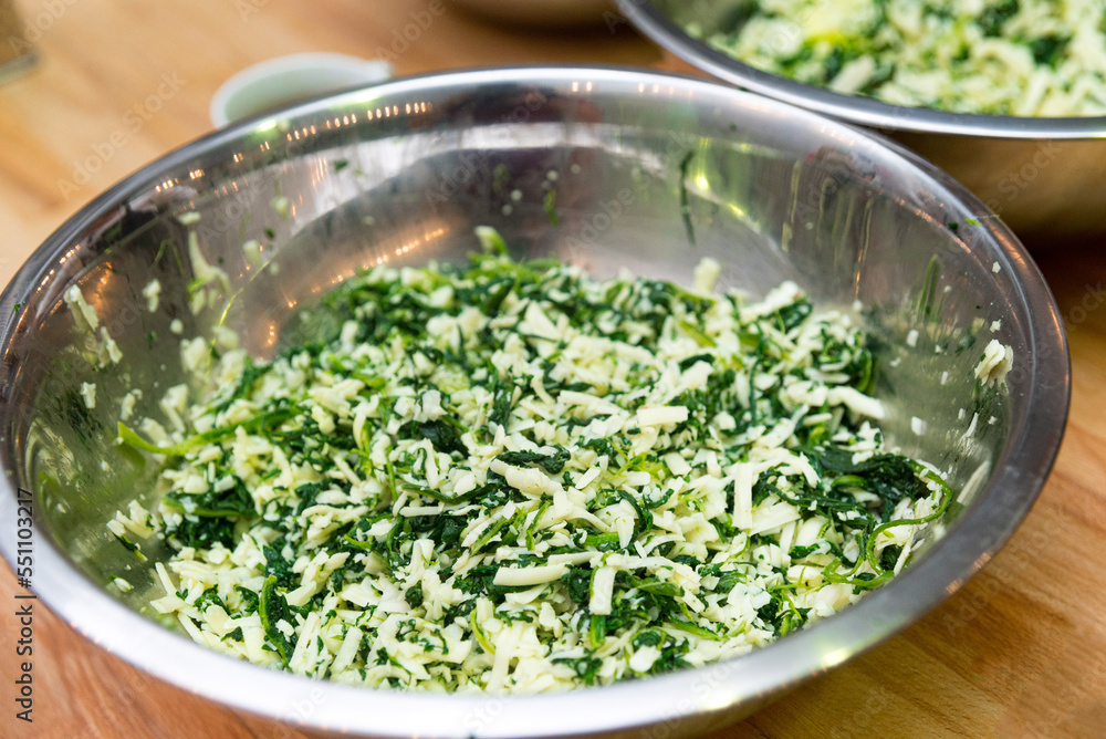A bowl of grated cheese mixed with chopped herbs. The filling for the cheese pie. A bowl of grated cheese mixed with chopped herbs. The filling for the cheese pie.