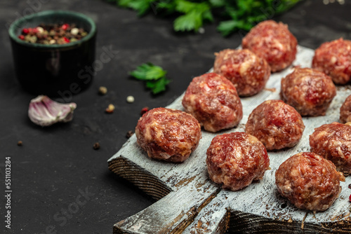 Fresh raw beef meatballs with spices on a cutting board on a dark background, banner, menu, recipe place for text, top view