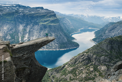 A person standing on the reef called trolltunga looking at the breathtaking view on norway lake and mountains. Norway famous place. Summer hiking.  photo