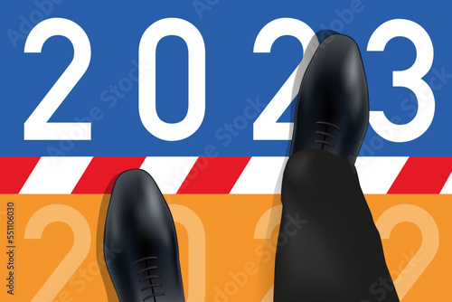 Carte de vœux 2023 montrant les pieds d’un homme vue du dessus qui franchissent une ligne symbolisant le passage à la nouvelle année.