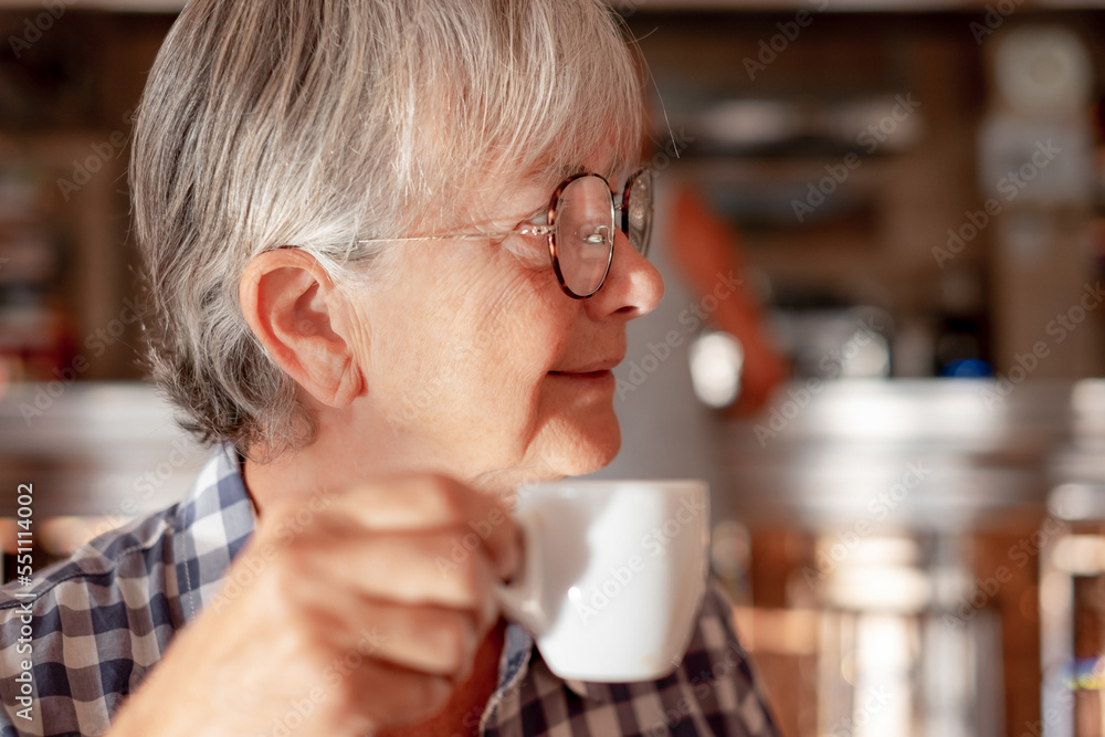 Attractive senior woman sitting indoor at a cafe table enjoying an espresso coffee cup - caucasian elderly lady with glasses relaxed has a break holding a coffee cup Attractive senior woman sitting indoor at a cafe table enjoying an espresso coffee cup - caucasian elderly lady with glasses relaxed has a break holding a coffee cup