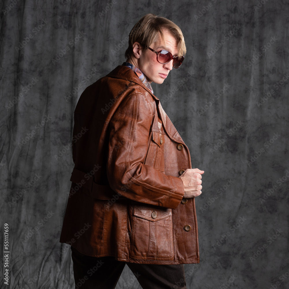 confident dude in a colorful shirt and brown leather jacket, a portrait in sunglasses in the studio on a gray background confident dude in a colorful shirt and brown leather jacket, a portrait in sunglasses in the studio on a gray background