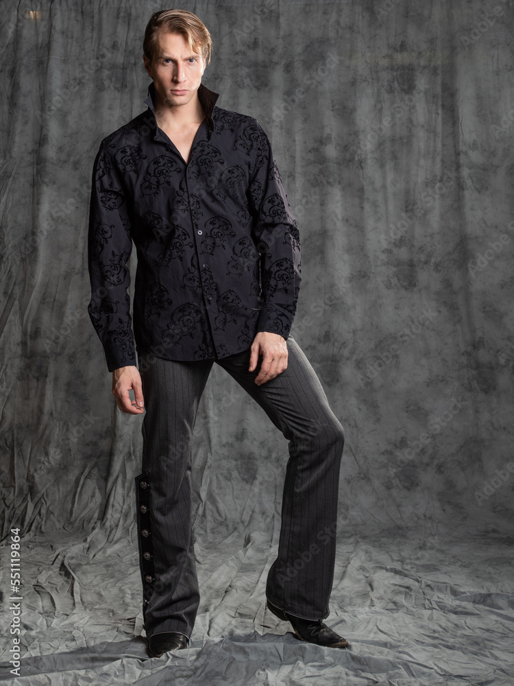 an attractive man in an elegant suit, shirt with embroidery. Photo in the studio on a gray background an attractive man in an elegant suit, shirt with embroidery. Photo in the studio on a gray background