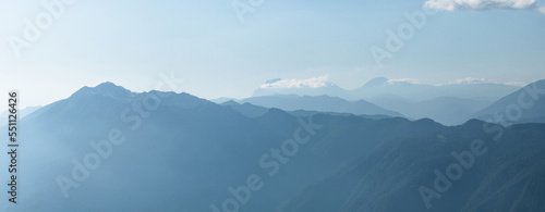 Light blue mountains in the distance, aerial perspective, mountain atmosphere. Beautiful mountain landscape, clouds over the peaks of the mountains,