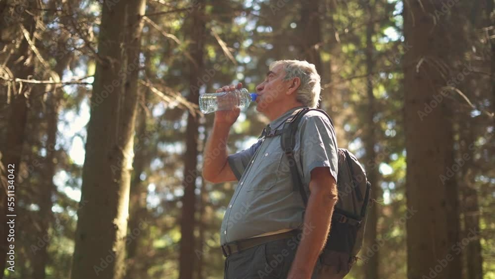 Senior hiker with backpack resting and drinking water in the forest. Active lifestyle. Senior hiker with backpack resting and drinking water in the forest. Active lifestyle.