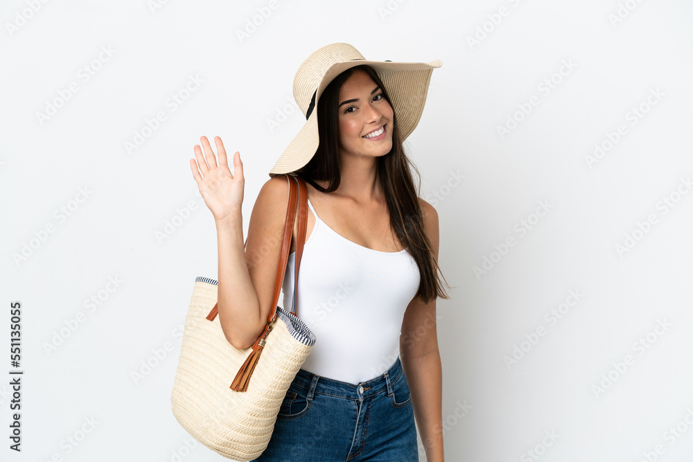 Young Brazilian woman with Pamela holding a beach bag isolated on white background saluting with hand with happy expression Young Brazilian woman with Pamela holding a beach bag isolated on white background saluting with hand with happy expression
