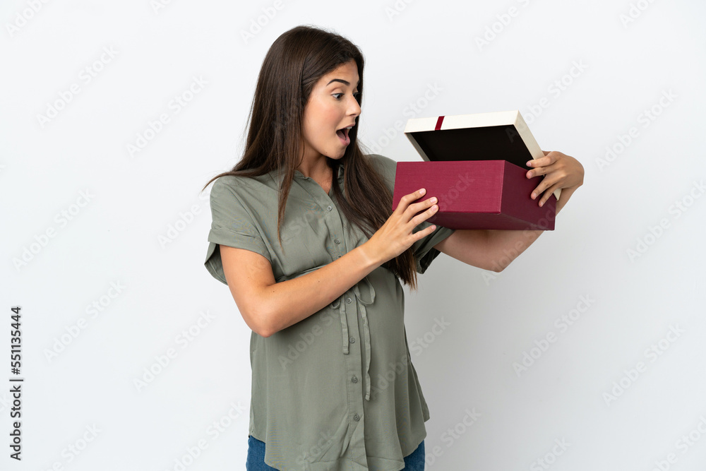 Fototapeta premium Young Brazilian woman isolated on white background pregnant and holding a gift with surprised expression