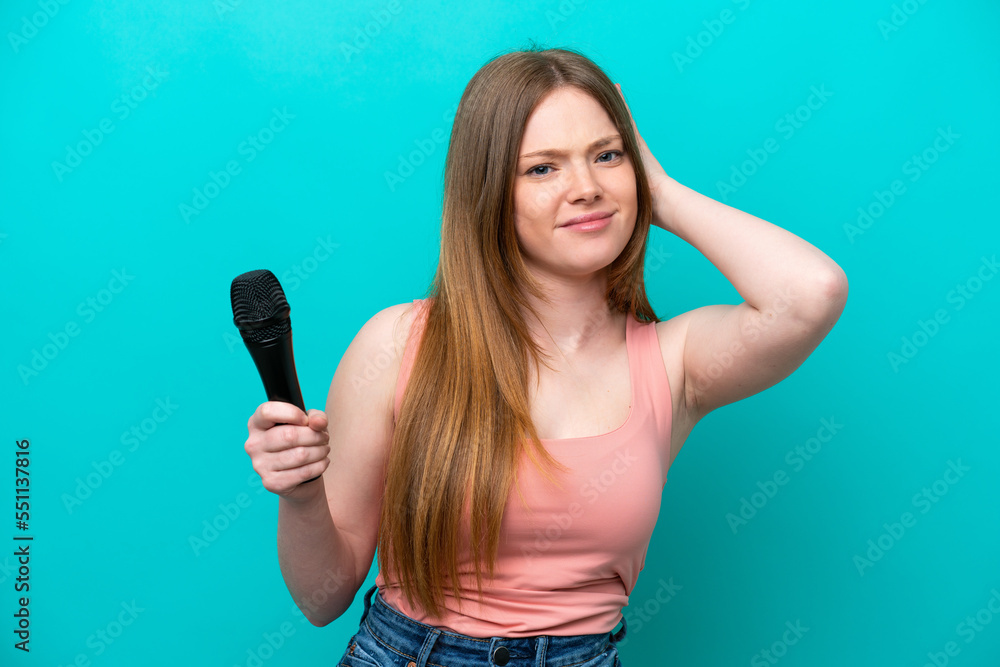Singer caucasian woman picking up a microphone isolated on blue background having doubts Singer caucasian woman picking up a microphone isolated on blue background having doubts