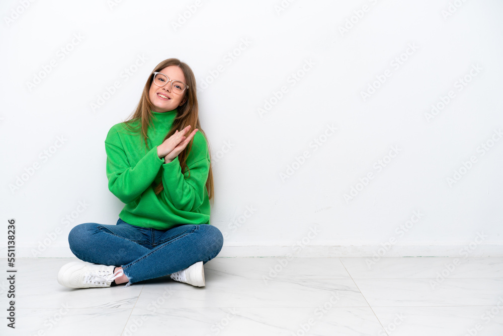 Young caucasian woman sitting on the floor isolated on white background applauding after presentation in a conference Young caucasian woman sitting on the floor isolated on white background applauding after presentation in a conference