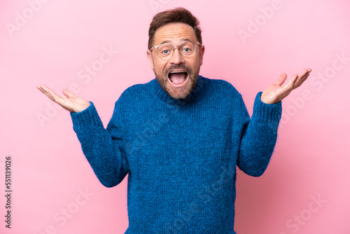 Middle age caucasian man isolated on pink background with shocked facial expression