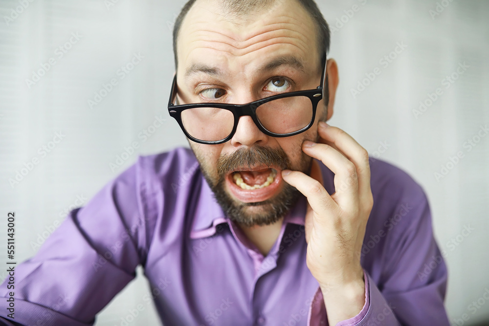 A cross-eyed bearded man is looking into the frame. Eye disease. The concept of an inexperienced specialist. Spy neighbor. A cross-eyed bearded man is looking into the frame. Eye disease. The concept of an inexperienced specialist. Spy neighbor.