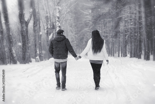 A loving couple on a winter walk. Man and woman on a date in the park in winter. Friends in a winter park