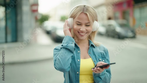 Young blonde woman smiling confident listening to music and dancing at street