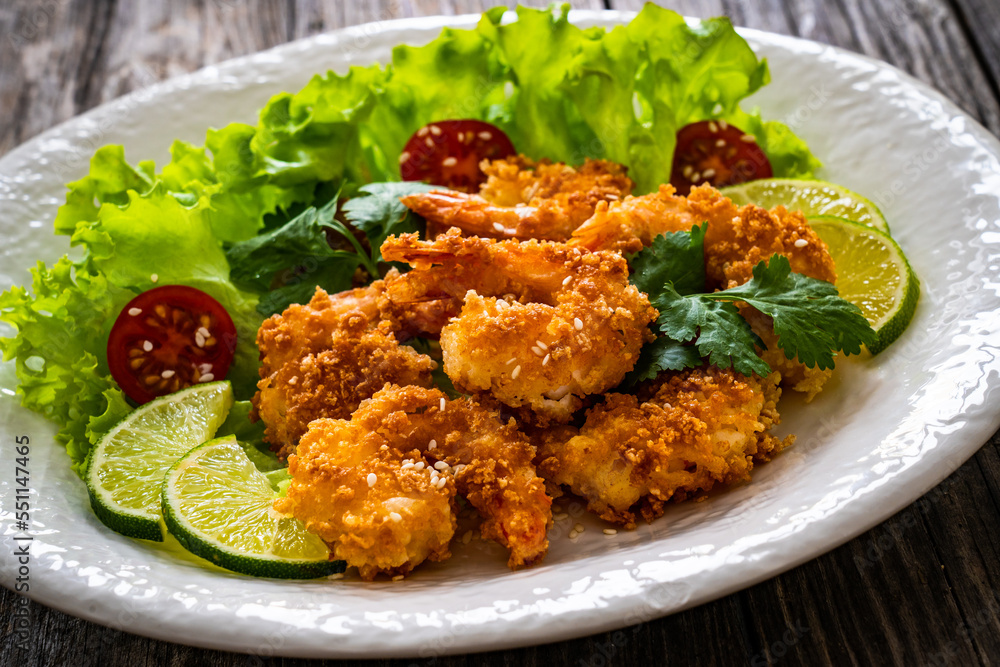 Fried panko prawns with lime, tomatoes and greens wooden table
Fried panko prawns with lime, tomatoes and greens wooden table