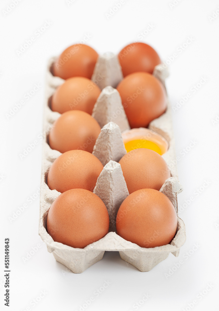Raw brown organic eggs in paper tray on white background Raw brown organic eggs in paper tray on white background