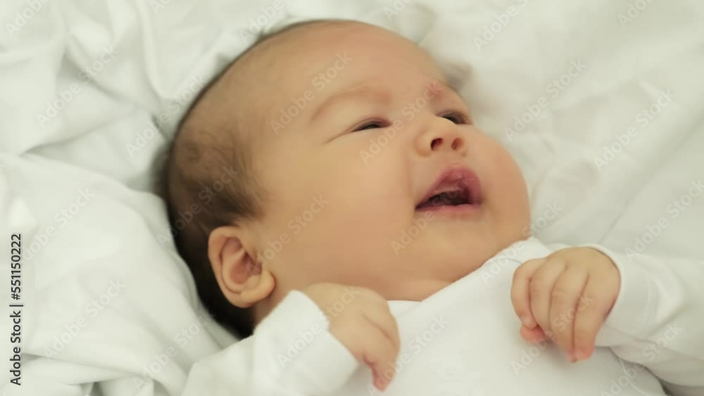 newborn baby smiles and laughs. shows emotions. baby lies on a white cloth newborn baby smiles and laughs. shows emotions. baby lies on a white cloth