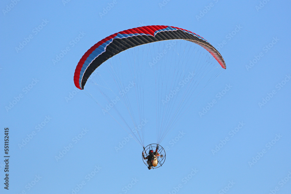 Paramotor pilot flying in a blue sky Paramotor pilot flying in a blue sky
