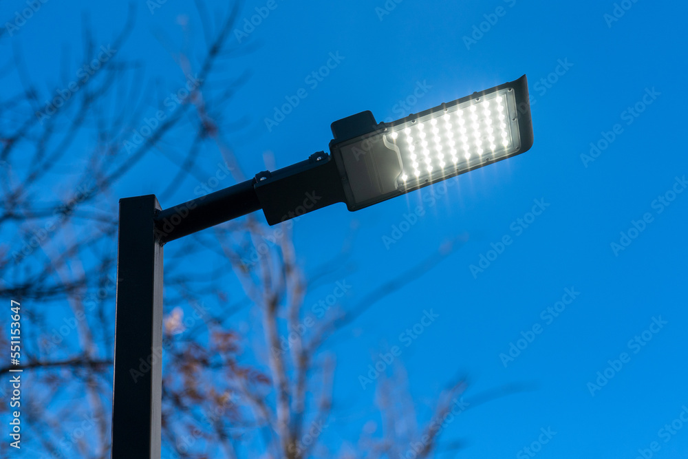 Modern LED city lamp. Street LED lamp. A lit street lamp. - obrazy, fototapety, plakaty 