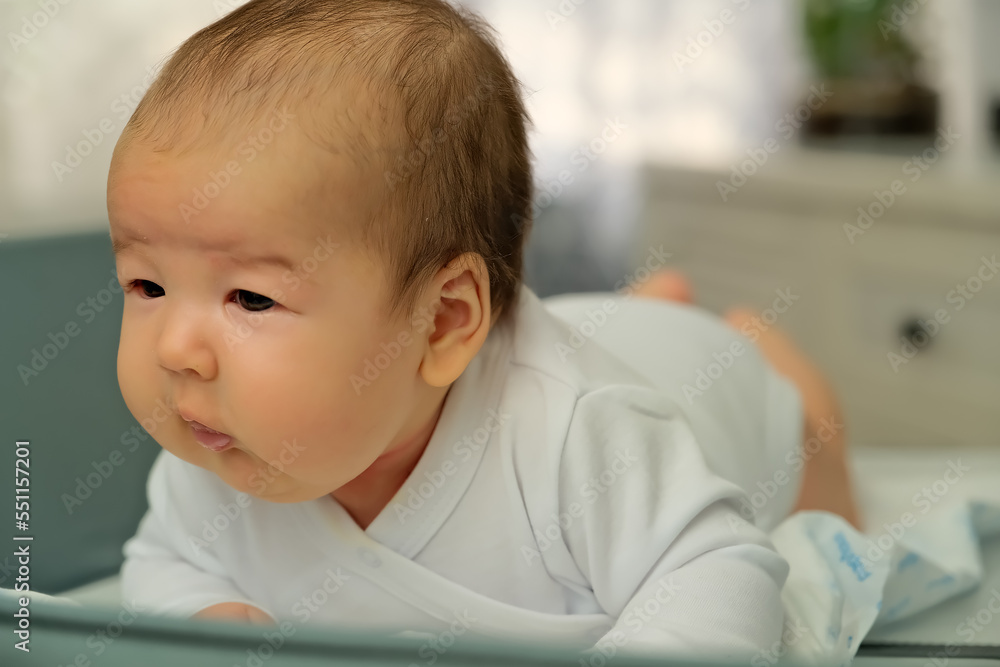newborn baby lies on the changing table. shows emotions. newborn baby learns to hold his head newborn baby lies on the changing table. shows emotions. newborn baby learns to hold his head