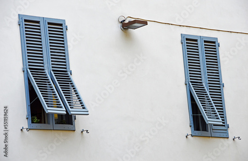 Two windows with blue shutters and an electric lantern on a buil photo