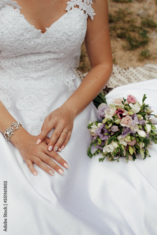 Bride in a stylish white wedding dress. Nearby lies a stylish bouquet of colorful flowers. Image for your creativity, design or illustrations. Bride in a stylish white wedding dress. Nearby lies a stylish bouquet of colorful flowers. Image for your creativity, design or illustrations.