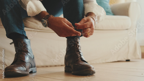 Close-up of legs of mature man putting on casual boots, tying shoelaces