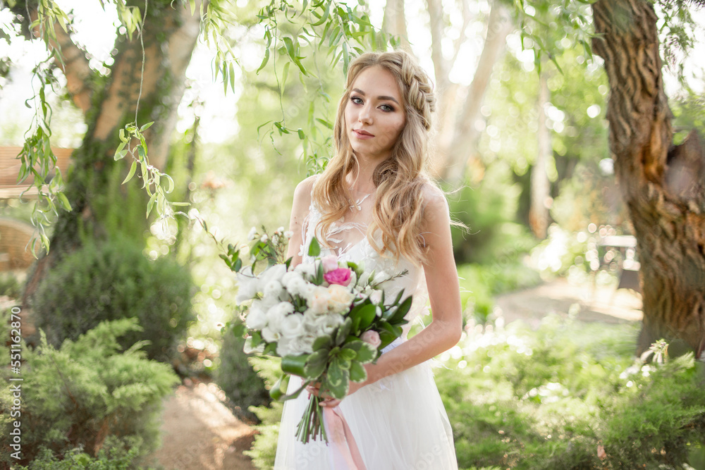 Beautiful woman bride in white wedding dress and bouquet in the garden Beautiful woman bride in white wedding dress and bouquet in the garden