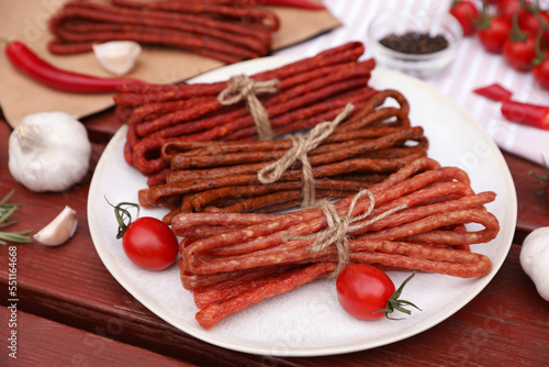 Bundles of delicious kabanosy with tomatoes on wooden table photo