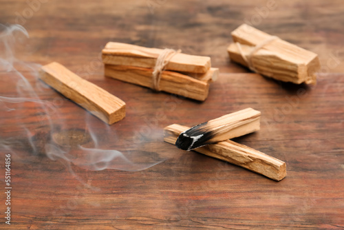 Palo Santo stick smoldering on wooden table