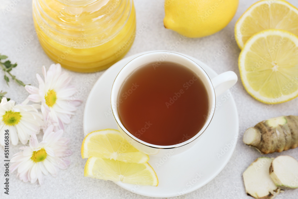 Cup of delicious tea with honey, lemon and ginger on white table, above view Cup of delicious tea with honey, lemon and ginger on white table, above view