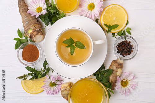 Flat lay composition with cup of delicious tea, honey and ginger on white wooden table