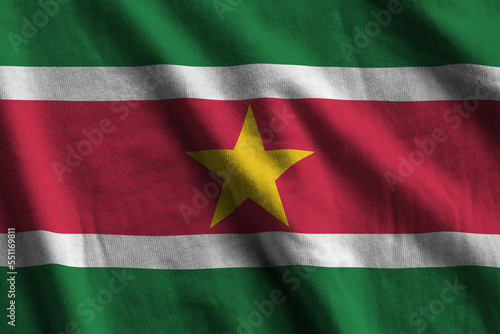 Suriname flag with big folds waving close up under the studio light indoors. The official symbols and colors in fabric banner photo
