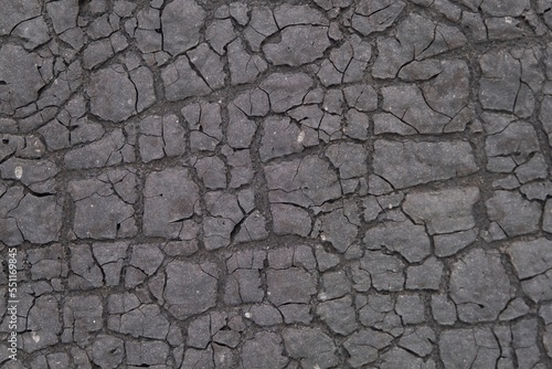 Weathered old dark gray ruberoid texture with numerous cracks and fractures, sun-scorched surface for use as a background.