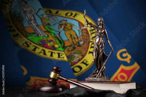 Idaho US state flag with statue of lady justice, constitution and judge hammer on black drapery. Concept of judgement and punishment photo