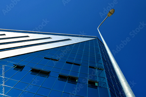 Low angle view of a lamppost near a modern building against blue sky