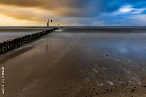 Beautiful sunset over wooden breakwater at the edge of Baltic sea