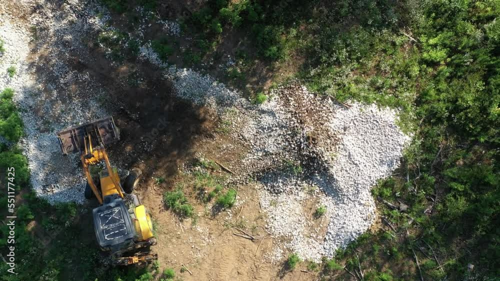 A modern tractor on a construction site from the air. A yellow wheel loader lifts and moves garbage. Heavy machinery is working at the facility. A modern tractor on a construction site from the air. A yellow wheel loader lifts and moves garbage. Heavy machinery is working at the facility.