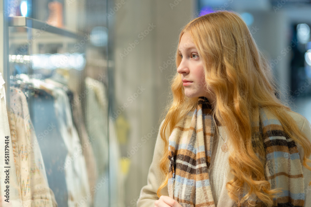Shopping. A young girl looks at shop window.