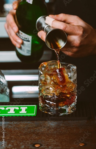 Фототапет Vertical shot of a human hands pouring vermouth and soda in an ice glass