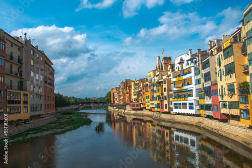 Colorful yellow and orange houses and famous house Casa Maso reflected in water river Onyar, in Girona, Catalonia, Spain. Church of Sant Feliu and Saint Mary Cathedral at background.
 photo