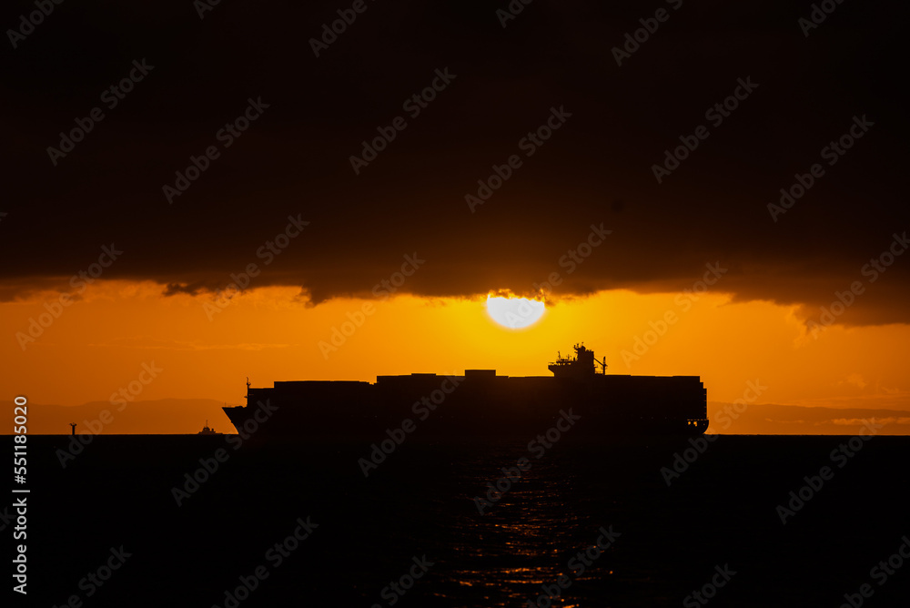 A container vessel is seen at sunset on the ocean