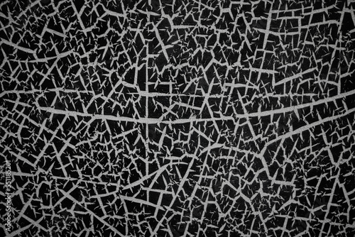 Abstract pattern of bright cracks on a black painted metal surface seems like lots of white spikes